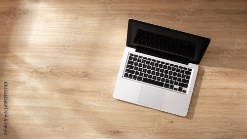 Obraz na plátne A laptop on light wooden background softly lit with sunlight from the window