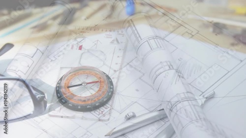 Camera panning over design desk, causing plans unrolling and glasses settling on compass for review