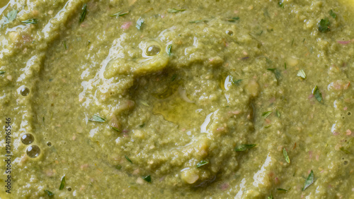 Macro background of fresh green herb sauce with spiral texture and olive oil drops
