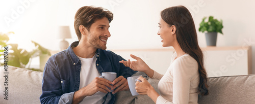 Fotografia Two people sit on a couch, smiling and talking with each other