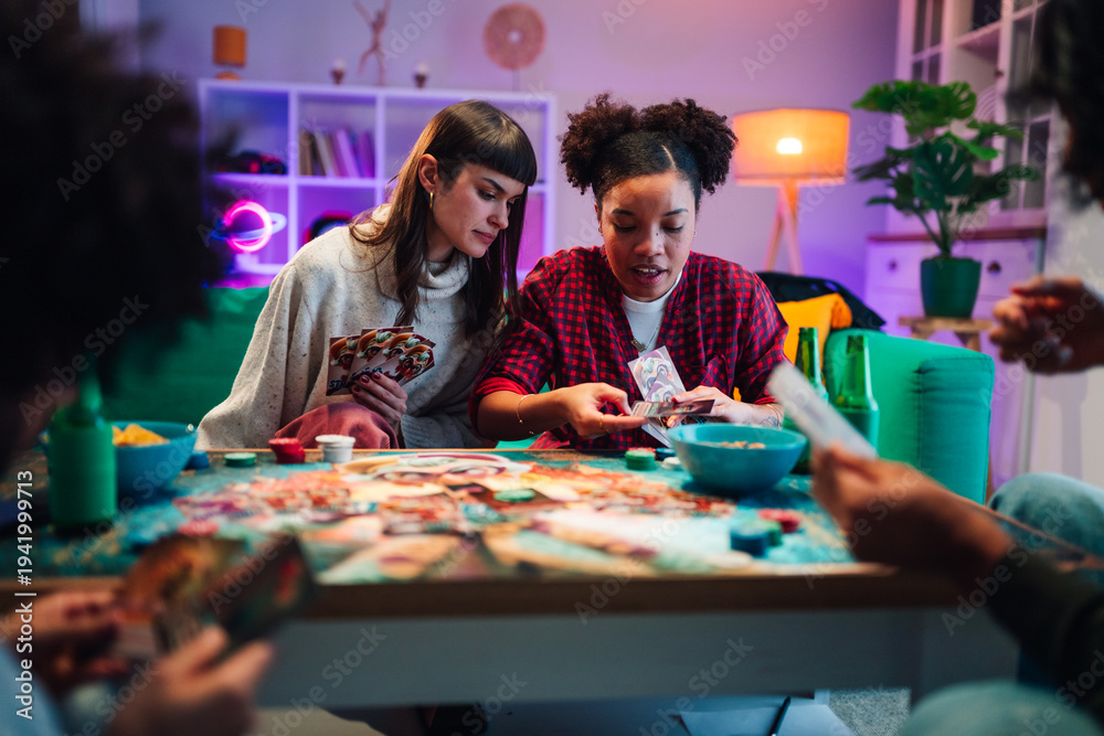Fototapeta premium Friends enjoying board game night at home, playing cards, socializing and having fun together