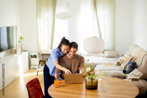 Couple enjoys time together while using laptop in bright living room