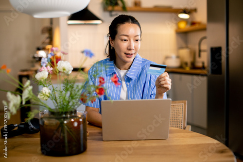Woman using laptop and hold...