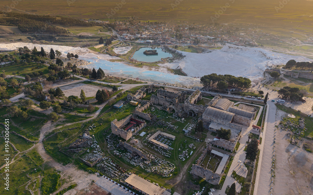 Fototapeta premium Aerial drone view of Hierapolis Antik Kenti and the famous Pamukkale travertines in Denizli, Turkey, showing ancient ruins, Roman theater, columns, and scenic landscape from above.