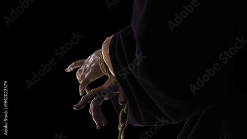 Hands of Jesus Christ tied with rope, black background.Holy week.