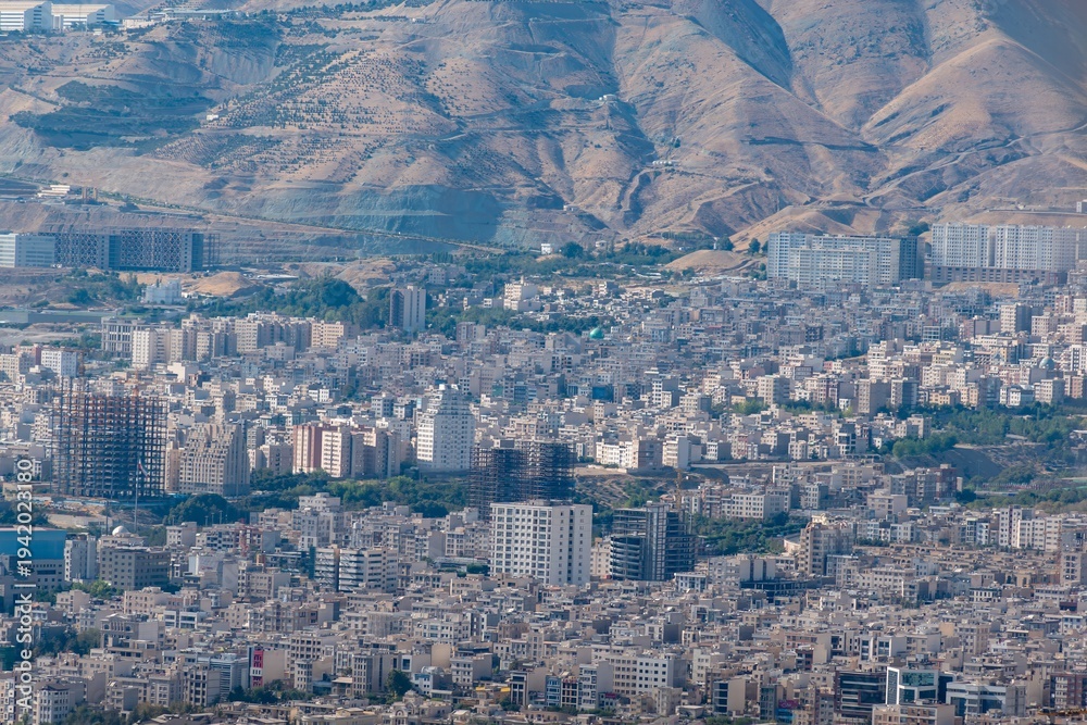 Obraz premium Tehran cityscape with dense buildings and arid mountains in the background