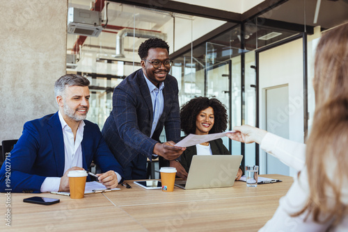 Diverse Business Team Sharing Documents During Collaborative Office Meeting Around Conference Table