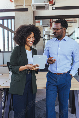Business Colleagues Discussing Project On Tablet In Modern Office During Casual Meeting And Collaboration