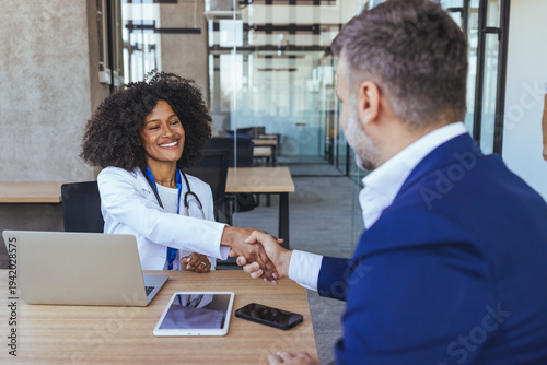 Female Doctor Shaking Hands With Male Patient In Professional Medical Consultation Office Setting