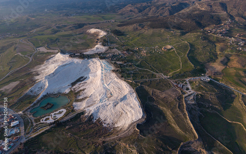 Aerial drone view of the famous Pamukkale travertines and thermal pools in Denizli, Turkey, showing the white calcium terraces, natural formations, and scenic landscape from above.