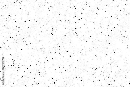 Black specks and tiny dots are randomly scattered across a bright white surface, creating a subtle visual texture