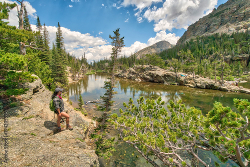Принти на полотні A woman is standing on a rocky ledge overlooking a lake