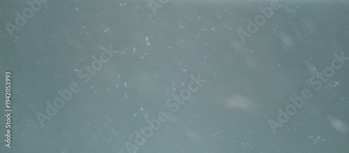 Abstract dust particles floating in light beam on dark blue background with bokeh effect and soft motion for overlay or atmosphere