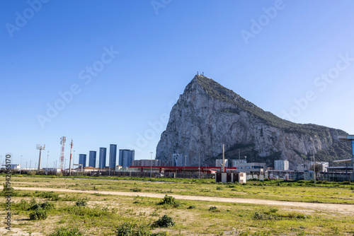 View of the Rock of Gibraltar and surrounding buildings against a clear blue sky during daylight hours