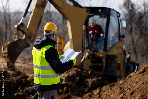 Photos Site supervisor coordinating excavator operator during trench excavation