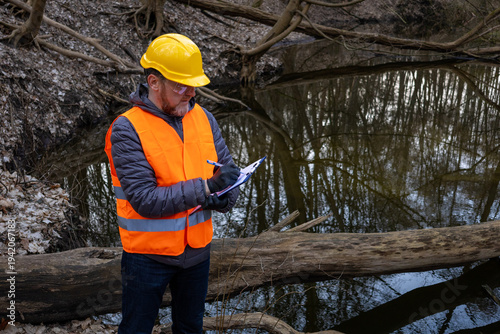 Foto Environmental engineer in hardhat and safety gear conducting river monitoring in a spring forest
