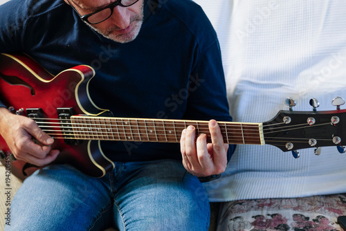 Mid adult man playing electric guitar at home