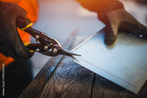 A man cuts a metal sheet with metal shears, construction work. Sheet metal shears snips cut edge of galvanized steel from roofing iron, outdoor work.