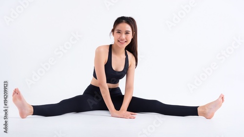 白背景で開脚ストレッチをする笑顔のフィットネス女性