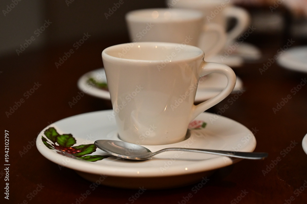 Obraz premium white ceramic coffee cups with saucers and spoons on wooden table, elegant espresso service at corporate event or wedding, hospitality setup with small coffee cups for guests, hot beverage station at 