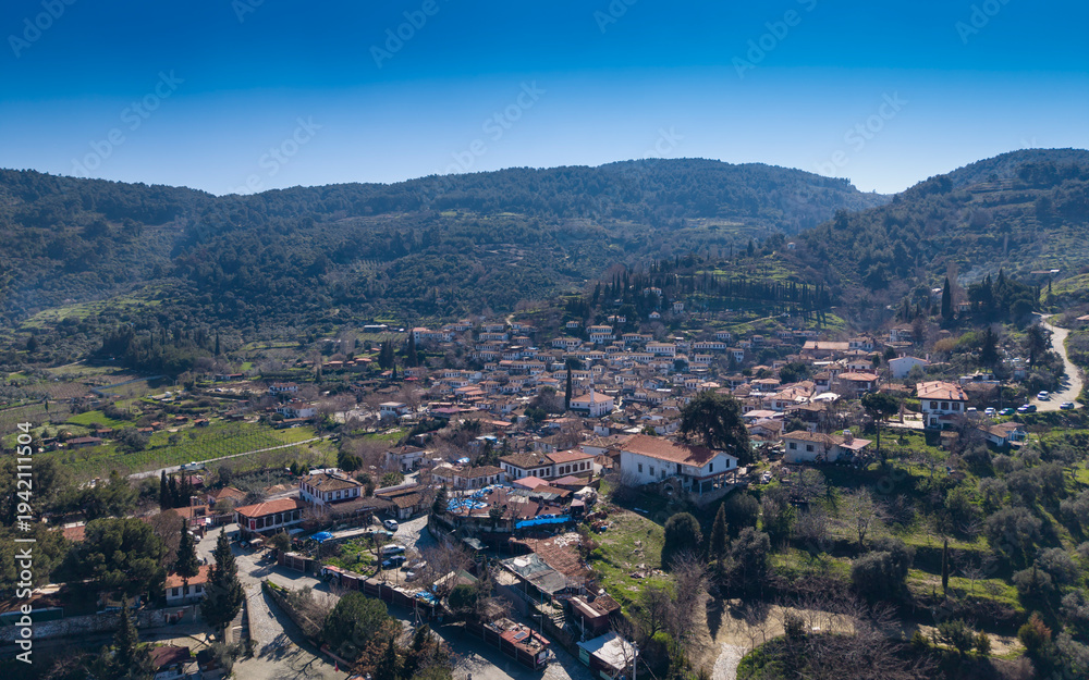 Obraz premium Aerial drone view of Şirince Köyü in Izmir, Turkey, showcasing traditional stone and wooden houses, narrow streets, vineyards, and the scenic hillside landscape from above.