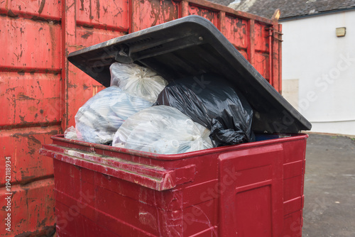Принти на полотні Overflowing red waste bin with garbage bags and open lid