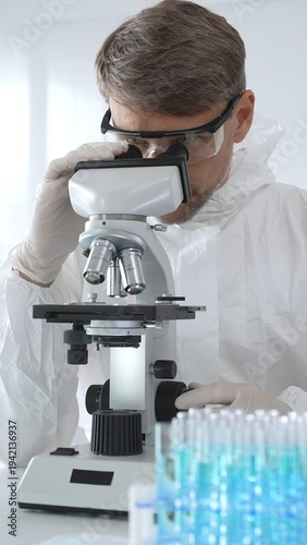 Cuadro en lienzo A male medical virologist in a medical gown and gloves examines viral samples un