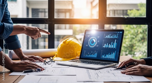 Collaborative Engineering Project Planning Meeting with Laptop Blueprints and Hard Hat in a Modern Office