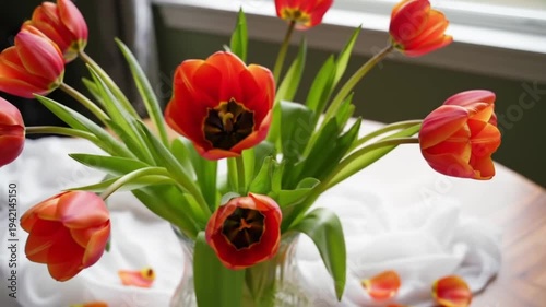 Vibrant orange tulips arranged in a vase on a wooden table.