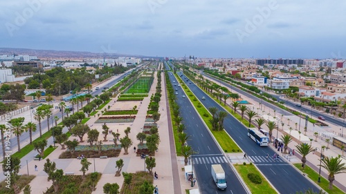 Aerial drone view of a newly renovated modern avenue featuring green public parks, sports courts, palm trees, and urban infrastructure in Agadir, Morocco.