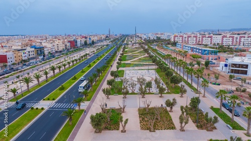 Aerial drone view of a newly renovated modern avenue featuring green public parks, sports courts, palm trees, and urban infrastructure in Agadir, Morocco.