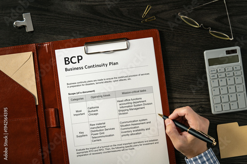 Business Continuity Plan: Realistic mock-up mock placed on  with calculator, pen, clips. Contributor-created fictional business document for illustrative purposes.