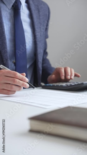 Professional accountant calculating expenses, documenting financial details on notepad while working at corporate desk. Audit and taxes in business