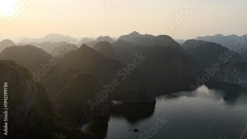 Canvas Print Beautiful sunrise over Ha Long Bay with limestone karst islands rising from the emerald water, traditional boats sailing between the cliffs in northern Vietnam