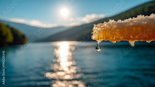 Honeycomb with dripping honey against a serene lake and mountain landscape