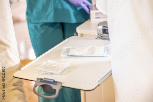Nurse preparing sterile dressing materials on bedside table for wound care and bandage change in nursing facility