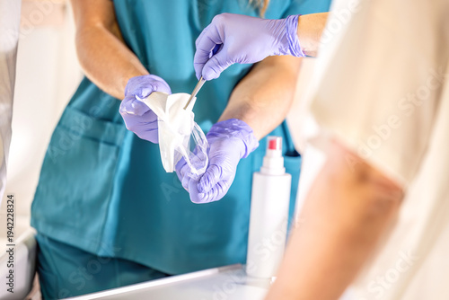 Nursing instructor receiving sterile gauze compress with forceps during clinical wound care training