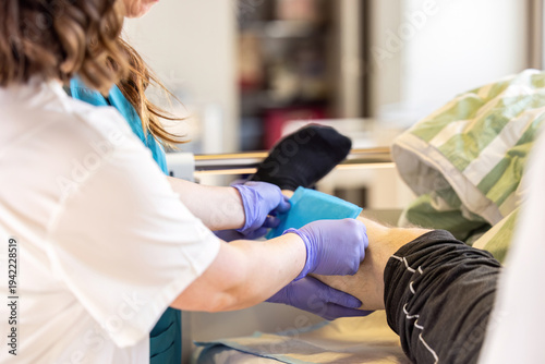 Nurse applying absorbent dressing to patient leg wound during clinical wound care treatment in hospital