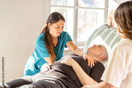 Nurses repositioning patient in hospital bed for pressure ulcer prevention and safe nursing care