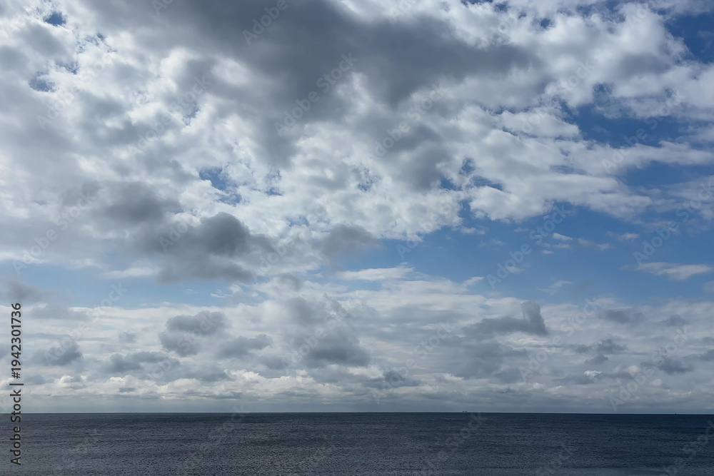 Obraz premium 波の穏やかな海と水平線に広がる白い雲と青い空