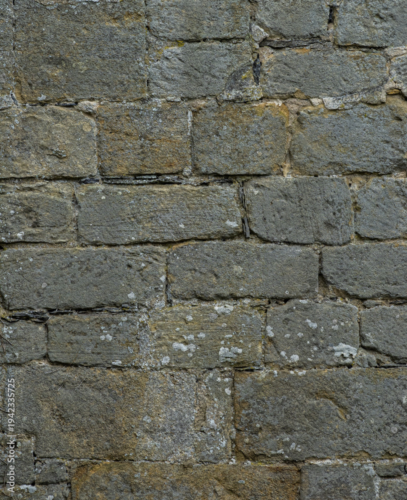 Fototapeta premium Medieval limestone stone wall background with weathered architectural texture