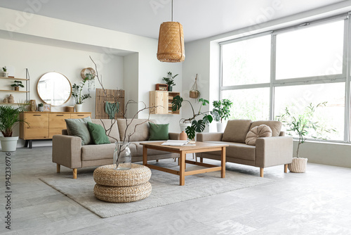 Interior of stylish living room with cozy grey sofas, coffee table and houseplants