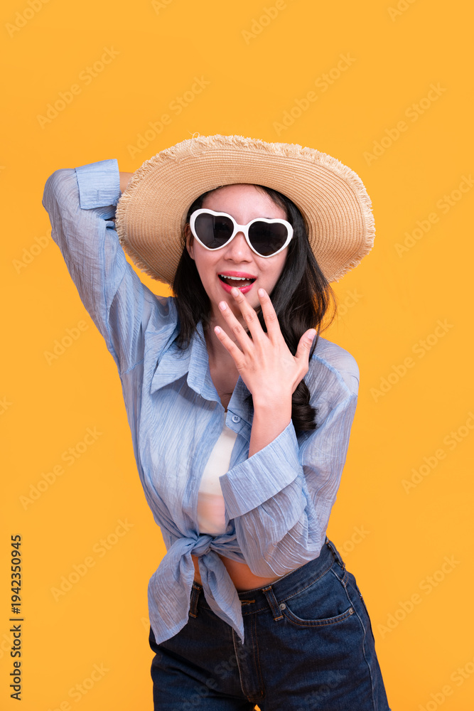 Fototapeta premium Excited Asian young woman in a sun hat and glasses to travel on holidays isolated on yellow copy space background. Travel, summer vacation, beach leisure concept.