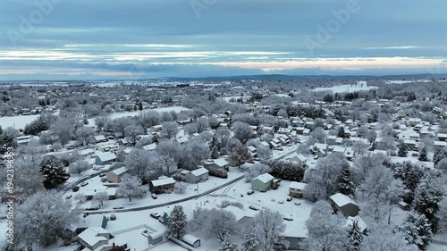 Peaceful and quiet American suburban neighborhood covered in fresh snow with icy trees and houses during calm winter morning. Aerial wide shot. Christmas season in Pennsylvania state.