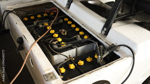 Battery terminal clamp. Close-up of black charging cable clamps attached to battery terminals for golf cart battery charging and selective focus maintenance concept.