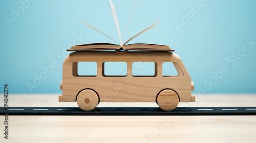 Wooden Toy Van with Open Book on Roof Driving on Road Symbolizing Travel and Education.