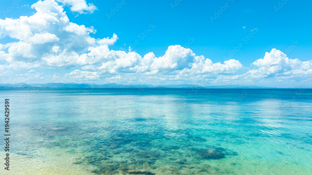 Fototapeta premium Tropical Nature clear sky and summer sea water under a clear blue sky with beautiful clouds and bright sunlight. Perfect for summer vacation and travel background 