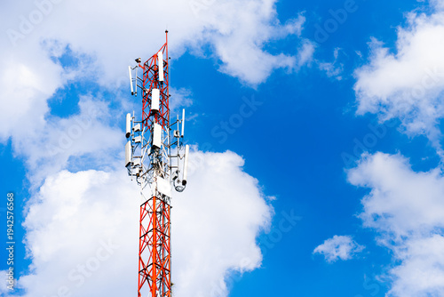 Telecommunication tower with antennas transmitting mobile signal against blue sky and  clouds. wireless network infrastructure, 5G communication technology, connectivity and modern digital network.