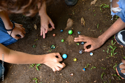 A group of children playing marbles on the ground, a traditional game.Children playing marbles.