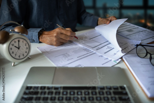 Photos close up shot, asian businessman working late on desk with laptop and documents